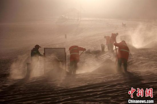 圖為敦煌市鳴沙山月牙泉景區(qū)“駱駝保姆”清理駱駝糞便?！垥粤?攝