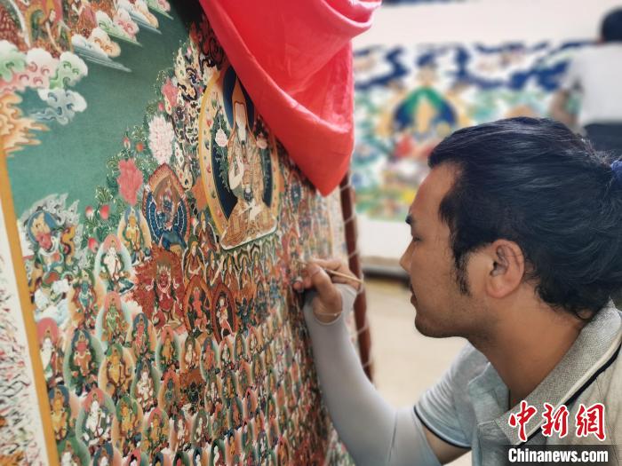 圖為更登才讓的徒弟繪畫唐卡?！?zhí)砀?攝