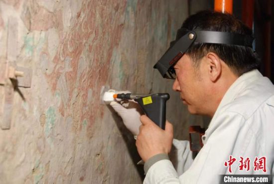 敦煌研究院研究員樊再軒進(jìn)行壁畫修復(fù)。(資料圖)張?jiān)莆?攝